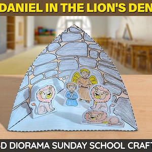 May include: A 3D diorama craft depicting "Daniel in the Lion's Den." The paper diorama features a triangular shape with a stone wall design. Inside are illustrated figures of Daniel, an angel, and lions. Text at the top reads "DANIEL IN THE LION'S DEN."