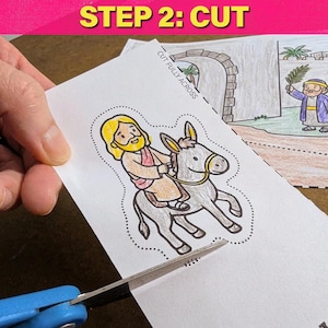 May include: A coloring page with a cartoon illustration of a person riding a donkey, being cut with blue scissors. The text "STEP 2: CUT" is in a pink banner at the top. The image is part of a larger scene.