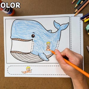 May include: A coloring page featuring a blue whale with a small figure inside. The whale is partially colored with blue, and an orange pencil is coloring the figure. Crayons, scissors, and glue are also visible.