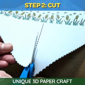 May include: A close-up of a white paper craft being cut with blue scissors. The paper has a decorative border with wheat and grass illustrations. The text "STEP 2: CUT" is at the top, and "UNIQUE 3D PAPER CRAFT" is at the bottom.