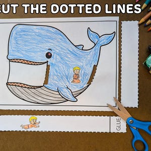 May include: A coloring page with a blue whale illustration, featuring a person inside the whale. The text "2. CUT THE DOTTED LINES" is at the top. Scissors and crayons are visible.