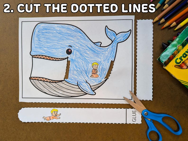 May include: A coloring page with a blue whale illustration, featuring a person inside the whale. The text "2. CUT THE DOTTED LINES" is at the top. Scissors and crayons are visible.