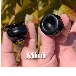 Pu&ograve; includere: Un paio di piccoli vasi in pietra nera lucida. Un vaso &egrave; mostrato di lato, l'altro dall'alto. La parola "Mini" &egrave; visualizzata in testo bianco tra i due vasi.