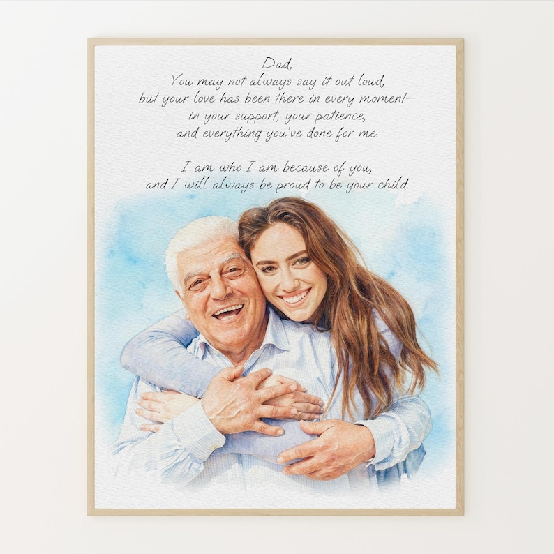 May include: A framed watercolor print featuring a smiling father and daughter embracing. The print includes a handwritten message to a father, with a blue watercolor wash background. The frame is a light brown color.