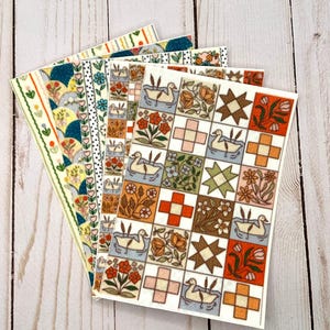 May include: A collection of patterned paper sheets featuring diverse designs. The sheets display floral, geometric, and duck patterns in green, blue, orange, and brown. These rectangular sheets are likely intended for crafts or scrapbooking.