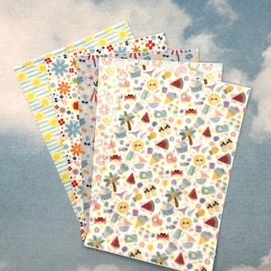 Könnte beinhalten: Vier Blätter bedrucktes Papier vor einem Himmelshintergrund. Die Designs umfassen Blumen, Sonnen und Sommer-Icons wie Palmen, Eiswaffeln und Wassermelonenscheiben. Die Farben sind hell und fröhlich.