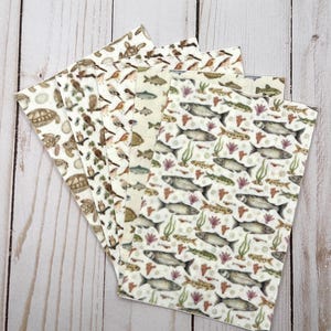 May include: A selection of patterned paper sheets with nature-themed designs. The sheets showcase illustrations of turtles, birds, and fish with aquatic plants. The colour palette includes shades of brown, green, and beige, creating a natural aesthetic.