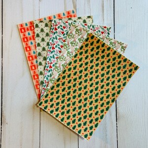 Op de afbeelding: Een verzameling papieren met kerstthema's. De papieren hebben verschillende ontwerpen, waaronder kerstbomen, hulstbladeren en bloempatronen. Het kleurenpalet omvat rood, groen en goud, wat een feestelijke en seizoensgebonden uitstraling creëert.