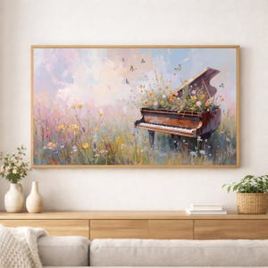 Puede incluir: Una obra de arte enmarcada representa un piano de cola en un campo de flores silvestres. La tapa abierta del piano est&aacute; llena de flores coloridas y mariposas revolotean a su alrededor. La obra tiene una paleta de colores suaves y pastel con un marco de madera.