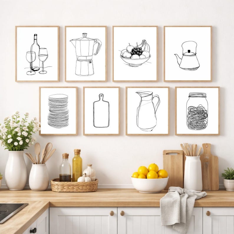 May include: A collection of eight framed black and white line art prints depicting kitchen and dining items. The prints include a wine bottle and glasses, a coffee maker, a bowl of fruit, a teapot, a stack of plates, a cutting board, a pitcher, and a jar.
