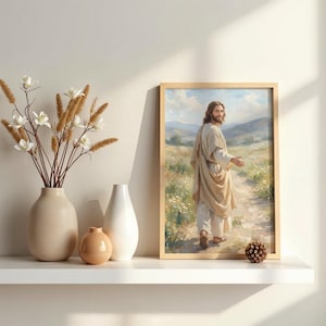 May include: A framed print of a religious figure in a light-colored robe, walking on a path through a field. The artwork is in a wooden frame and is displayed on a white shelf with decorative vases and a dried flower arrangement.