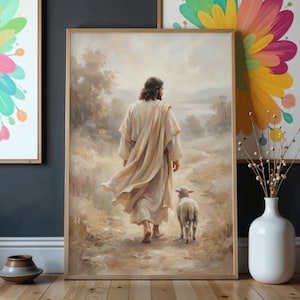 May include: A framed print depicts a figure in flowing robes walking with a lamb on a path. The artwork features a soft, muted color palette with beige, brown, and cream tones. The image evokes a sense of peace and serenity, suitable for home decor.