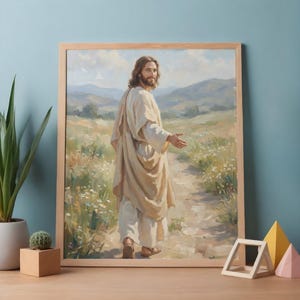 May include: A framed print depicts a figure in flowing robes walking on a path through a field. The artwork features soft colors, with a focus on the central figure and a serene landscape in the background. The frame is made of light-colored wood.