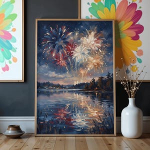 May include: A framed painting shows a fireworks display over a lake at night. The artwork features red, white, and blue bursts of light against a dark blue sky. The water reflects the colourful explosions and the lights of a distant town.
