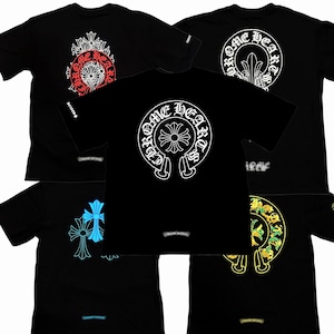May include: A collection of five black short-sleeve t-shirts featuring the Chrome Hearts logo. Each shirt displays a circular graphic with a cross emblem and the text Chrome Hearts in white, red, blue, or yellow, with a small logo on the sleeve.