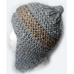 以下が含まれることがあります： グレーとブラウンのニット帽にスパンコールが付いています。帽子には耳と首を覆うことができる長いフラップが付いています。