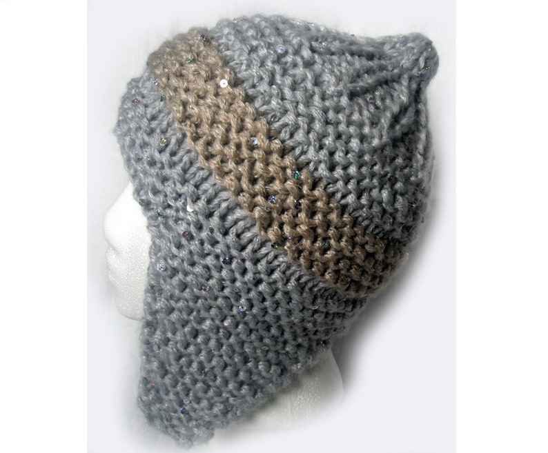 以下が含まれることがあります： グレーとブラウンのニット帽にスパンコールが付いています。帽子には耳と首を覆うことができる長いフラップが付いています。