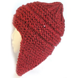 以下が含まれることがあります： 耳と首を覆う長いフラップが付いた赤いニット帽。帽子は質感のあるニットで、小さなスパンコールで飾られています。