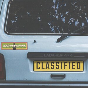 A 1990s station wagon with the magnet on the bumper. The license plate reads "classified."