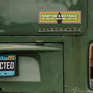 The back of a vintage Volkswagen with the bumper magnet on it. The license plate number is blacked out and says "redacted."