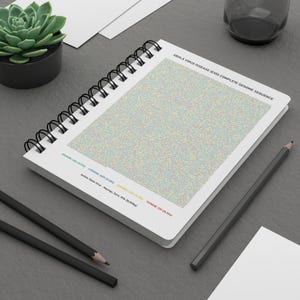 May include: A spiral-bound notebook with a detailed, colorful graphic of the Ebola virus genome sequence. The text "EBOLA VIRUS DISEASE (EVD) COMPLETE GENOME SEQUENCE" is at the top. Two black pencils and a small potted succulent are also visible.