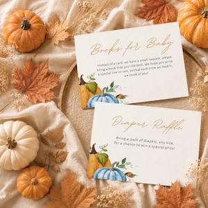 Puede incluir: Dos tarjetas rectangulares blancas con texto cursivo dorado e ilustraciones de calabazas en acuarela. La tarjeta superior dice Books for Baby con un poema, y la inferior dice Diaper Raffle con instrucciones para un baby shower.
