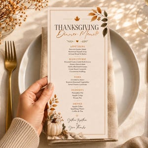 Könnte beinhalten: Eine rechteckige Thanksgiving-Menükarte mit cremefarbenem Hintergrund, herbstlichen Blattillustrationen und einem kleinen weißen Kürbis am unteren Rand. Der Text listet Vorspeisen, Hauptgerichte, Beilagen, Desserts und Getränke auf.