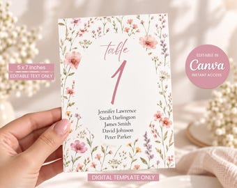 May include: A 5 x 7 inches rectangular table number card featuring a white center oval with the text table 1 and a list of names. The border is decorated with watercolor illustrations of pink, yellow, and purple wildflowers and greenery.