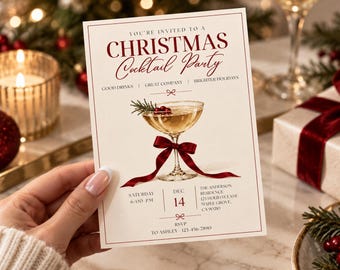 May include: A rectangular Christmas cocktail party invitation card featuring a gold-rimmed coupe glass with a red ribbon, cranberries, and rosemary. The text reads: YOU'RE INVITATION TO A CHRISTMAS COCKTAIL PARTY, GOOD DRINKS, GREAT COMPANY, BRIGHTER HOLIDAYS, SATURDAY 6:00 PM, DEC 14, THE ANDERSON RESIDENCE 123 HOLIDAY LANE MAPLE GROVE, CA 90210, RSVP TO ASHLEY 123-456-7890.