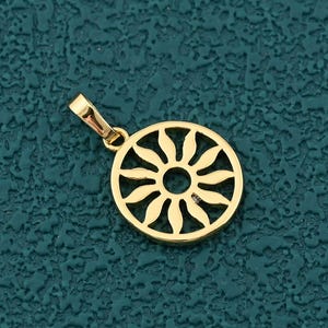 Peut inclure: Pendentif doré avec un motif de soleil dans un cercle. Le pendentif est doté d'une petite boucle pour une chaîne. Le fond est de couleur teal texturée.