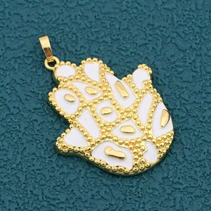 以下が含まれることがあります： 白エナメルとゴールドアクセントのゴールドトーンのハムサハンドペンダント。ペンダントは、ビーズの縁取りとチェーン用のループを備えた詳細なデザインが特徴です。ハムサハンドは保護と幸運の象徴です。