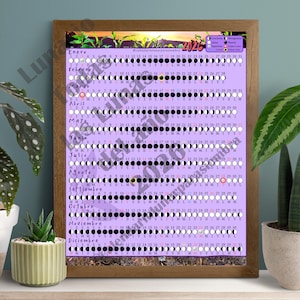 Puede incluir: Un calendario enmarcado de 2026 con un fondo lavanda, que muestra las fases lunares de cada mes. El calendario está en español, con el nombre y las fechas de cada mes visibles. El marco es de color marrón oscuro.