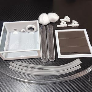 May include: A white ant farm kit with clear tubes, a white rectangular enclosure, and a solar panel. The kit includes cotton balls and small white plastic structures. The text "ANT FORCE" is visible on the enclosure.