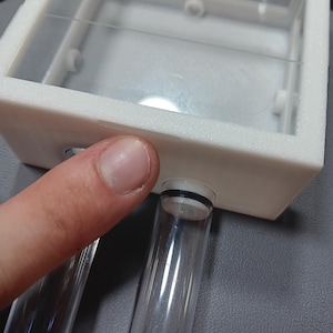 my finger pointing at the rear notch of the lid which is used to open it.