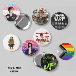 May include: A collection of 1.5 inch circular pin-back buttons featuring various Stray Kids designs, including portraits of members, a cartoon character, text graphics like 'bet on what you want' and 'PUT EM UP', and a rainbow pride flag with the Stray Kids logo.