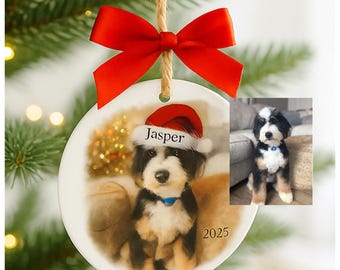 May include: A round ceramic Christmas ornament featuring a dog wearing a Santa hat with the name "Jasper" on it. The ornament has a red bow and a jute string for hanging. The year "2025" is printed on the ornament.