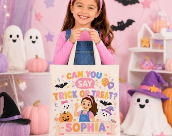 May include: A white canvas tote bag featuring a colorful Halloween-themed graphic with the text "CAN YOU SAY TRICK OR TREAT?" and the name "SOPHIA" printed in a banner. The design includes a cartoon character, ghosts, bats, and pumpkins.