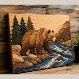 May include: A rectangular wooden wall art piece featuring a layered intarsia design of a brown bear walking along a rocky riverbank. The scene includes dark green pine trees, a flowing blue river with white water, and tan mountains in the background.