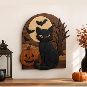 May include: A layered wooden wall art piece featuring a black cat sitting next to an orange jack-o'-lantern. The background displays a light-colored full moon, three black bats in flight, and a dark brown leafless tree against a dark wood panel.