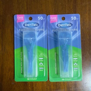 May include: Two identical packages of DenTek floss threaders, each containing 50 count. The blue and green packaging features the text DenTek Floss Threaders, Case Included, Works with any floss, and Use with: Bridges, Implants, Braces.