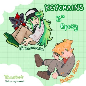 May include: Illustration of two 3-inch epoxy keychains. One keychain features a character with green hair and a black and white hat, holding a small creature. The other keychain shows a character with orange hair and a red bow tie. Text includes "KEYCHAINS", "3" Epoxy", "N Harmonia", and "Daiba Nana".