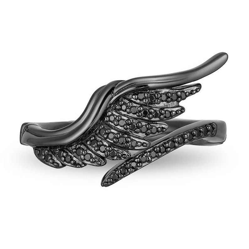 May include: A black ring with a wing design. The wing is detailed with small black stones. The ring has a sleek, modern look, with a curved wing shape that wraps around the finger. The ring is set against a white background.