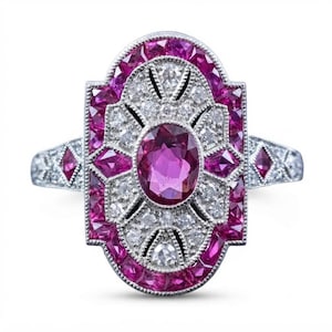 Peut inclure: Une bague de forme ovale avec une pierre précieuse rose centrale de taille ovale, entourée d'une bordure décorative de petites pierres roses et de pierres blanches claires serties dans une monture en métal argenté avec des détails sur l'anneau.