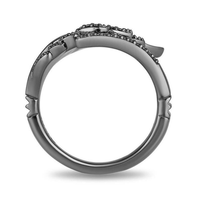 May include: A dark gray ring with a floral design. The ring has a smooth, polished band and a detailed floral pattern on the top. The ring is set against a white background, highlighting its intricate design.