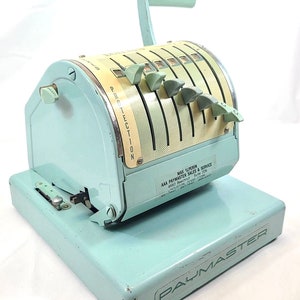 May include: A light blue vintage Paymaster time clock with a lever handle and six dials. The clock has a yellow and white face with the word "PROTECTION" printed on it. The clock is on a light blue base with the word "PAYMASTER" printed on it. The clock has a label with the text "MAX ALPERIN AAA PAYMASTER SALES & SERVICE 4660 Beechnut Suite 209 HOUSTON TEXAS 77096".