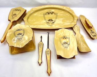 May include: A vintage vanity set with a yellow and white marbled finish. The set includes a tray, a brush, a small box, two tools, and two small containers.
