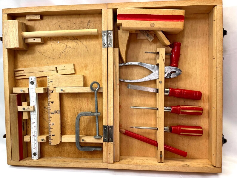 May include: A vintage wooden tool kit, open to reveal various carpentry tools. The kit includes a mallet, ruler, pliers, screwdrivers, and a clamp. The tools are arranged within the wooden box, showcasing a collection of essential instruments for woodworking and repair.