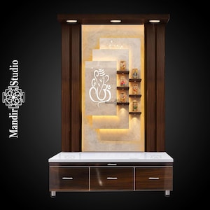 Könnte beinhalten: Ein maßgefertigter Holztempel mit weißem Marmor-Effekt-Hintergrund. Er zeigt ein weißes Ganesh-Symbol und kleine Regale mit religiösen Figuren. Der Sockel hat drei Schubladen mit silbernen Griffen. Der Tempel wird von warmem Licht beleuchtet.