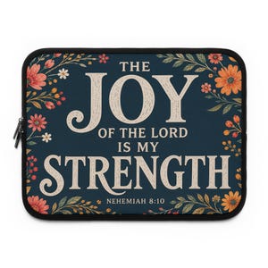 May include: A rectangular dark blue laptop sleeve featuring a floral border with orange, red, and white flowers. The text in the center reads: THE JOY OF THE LORD IS MY STRENGTH NEHEMIAH 8:10. The sleeve has a black zipper and rounded corners.