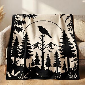 May include: A black and cream-colored throw blanket featuring a pixelated landscape design. The pattern displays a large crow perched on a tree branch centered in front of a full moon, surrounded by a dense forest of pine trees and mountain peaks.